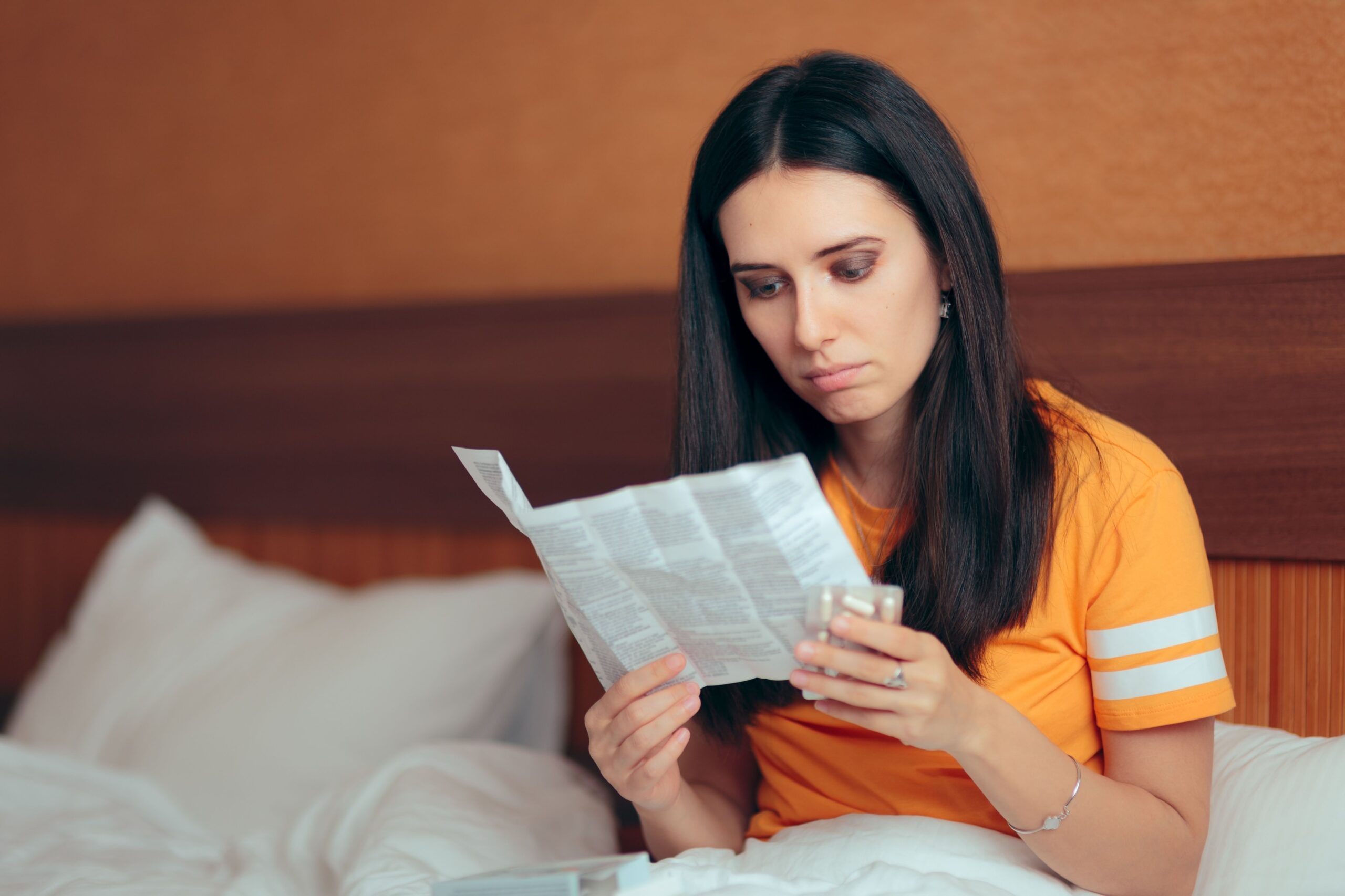 Woman reading medical leaflet about possible risks and side effects of prenatal vitamins