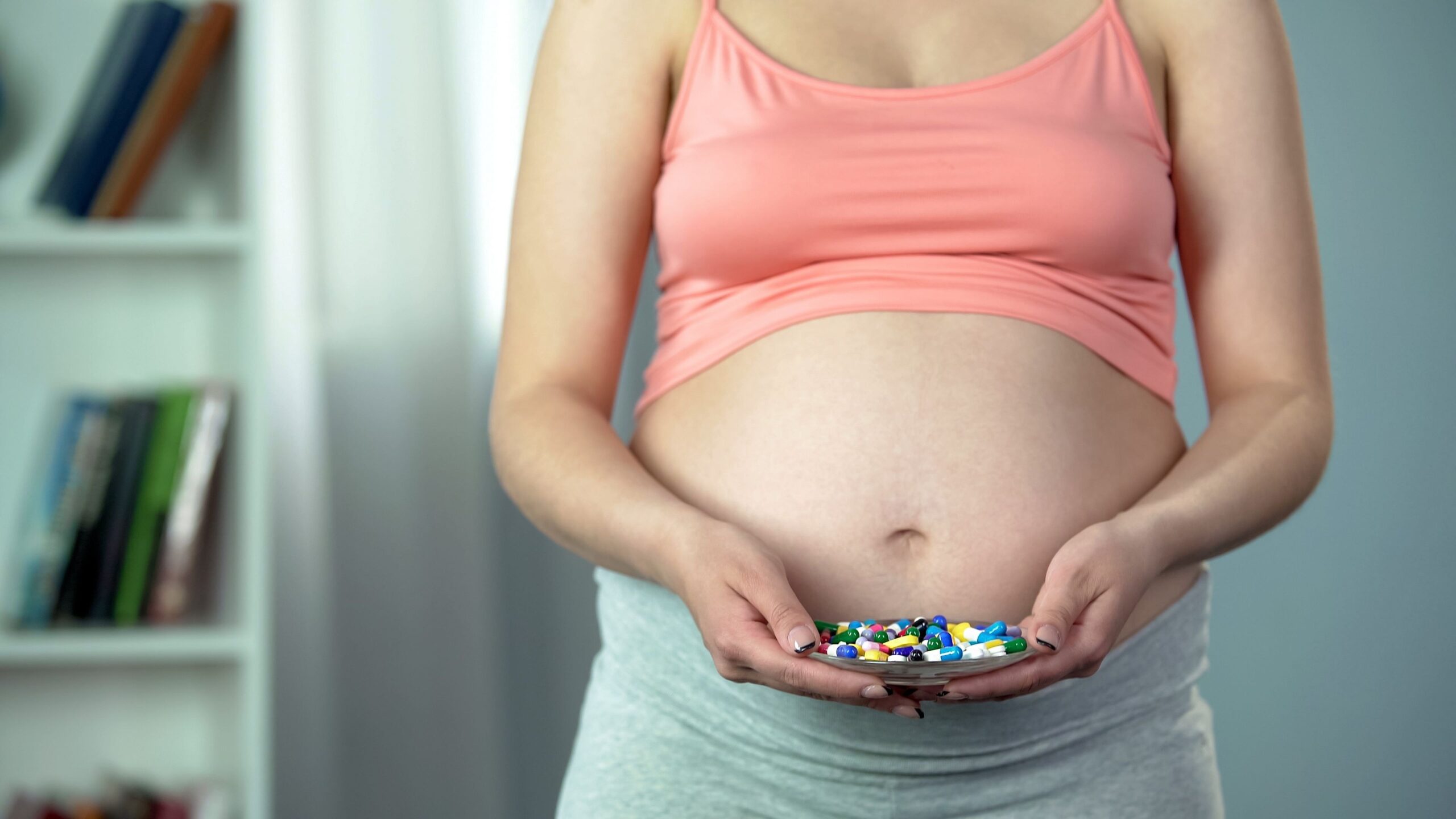 Pregnant woman holding prenatal vitamins in her hands