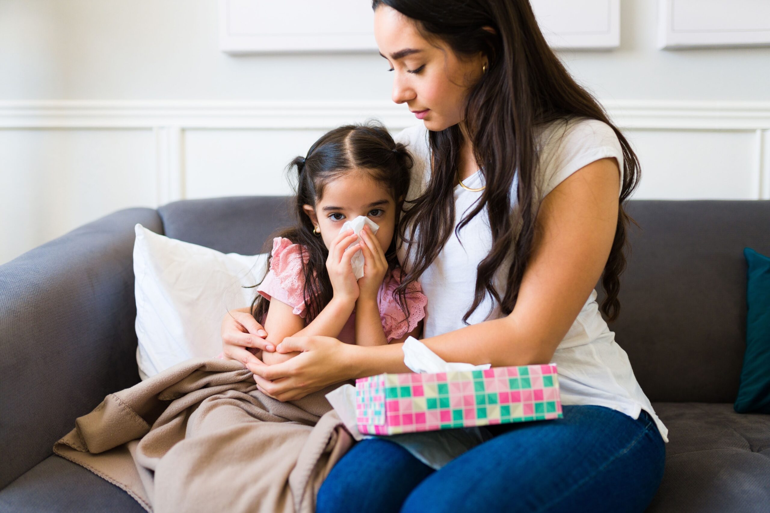 Little girl sick with the flu being comforted by her mother