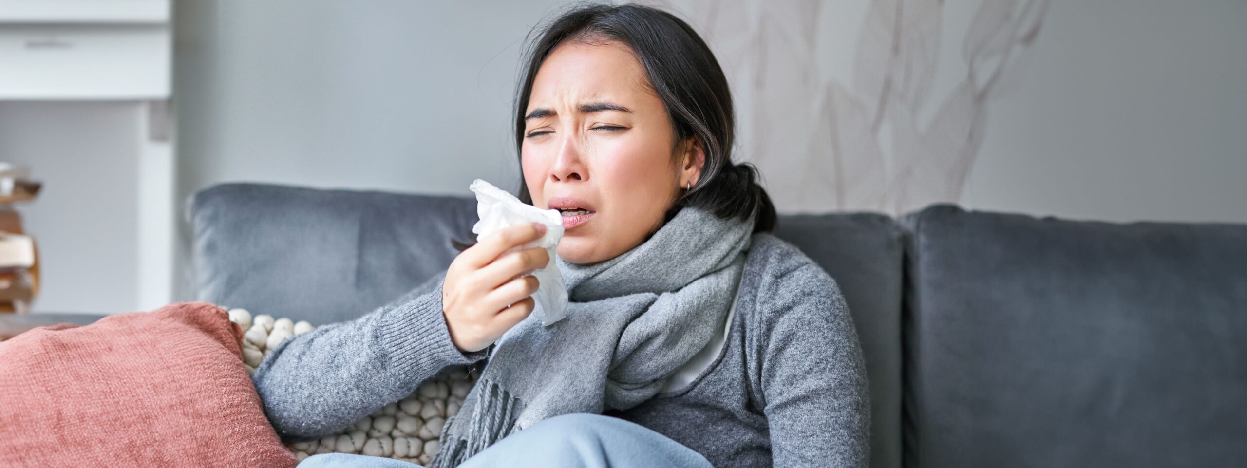 Asian woman sneezing into a napkin