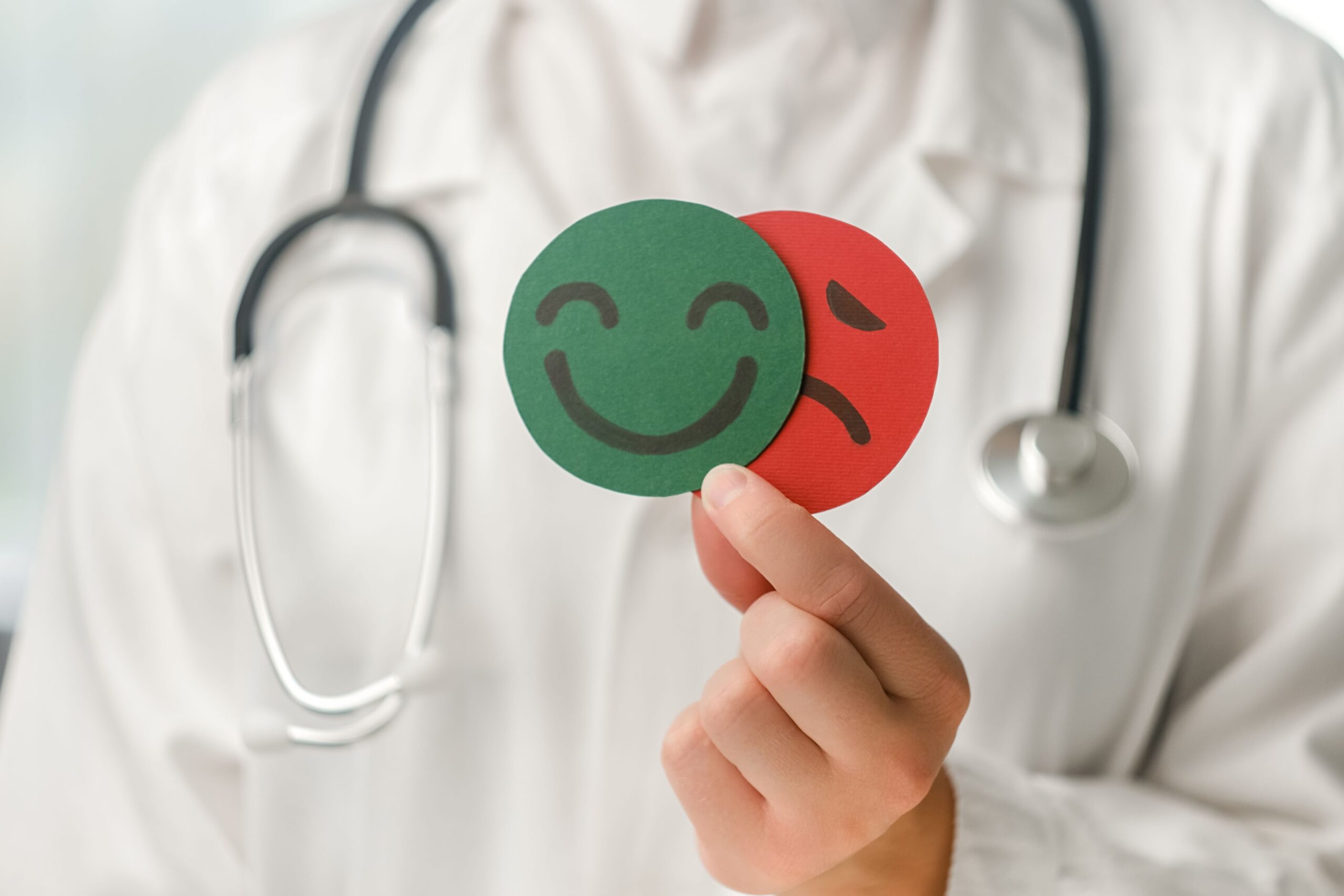 Doctor holding a smiley face and a frownie face